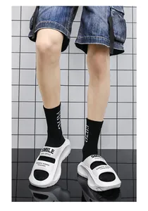 Detail view of white EVA slides with black SMILE text worn with socks on grid background