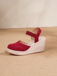 Detalle de sandalia de cuña tipo alpargata en ante rojo con suela de cuerda trenzada