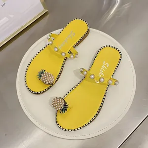 Detailed view of yellow flat sandals with pearl straps and pineapple toe design