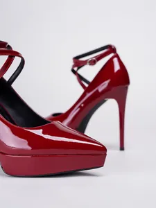 Primer plano de tacones de aguja con plataforma de charol rojo y puntera afilada