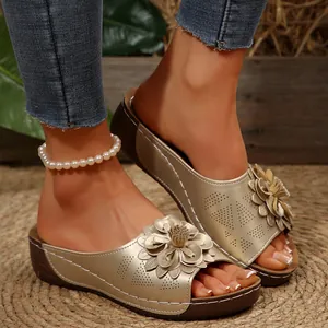 Detalle de sandalias de cuña doradas para mujer con decoración de flores chic.