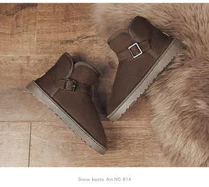 Pair of brown suede winter snow boots with buckle detail on a warm fur rug backdrop