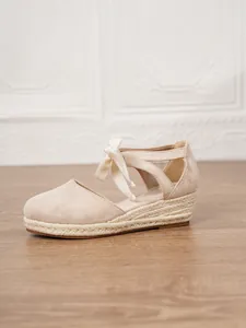 Detalle lateral de alpargatas con cuña beige para mujer con lazo en el tobillo
