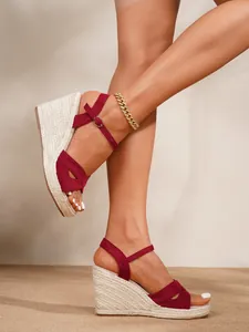 High-quality close-up of red suede wedge sandals with straw platform and ankle strap