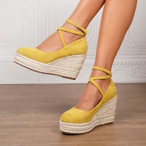 Elegantes sandalias de cuña amarillas con plataforma de esparto y correas al tobillo.