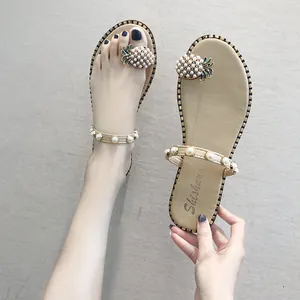 Detailed close-up view of elegant flat thong sandals with pearl pineapple decor