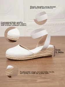 Detalle de sandalias de cuña de lona blanca con plataforma de esparto tejida a mano