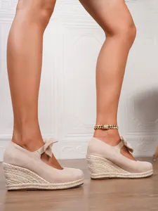 Vista detallada de alpargatas de cuña en ante beige con plataforma tejida