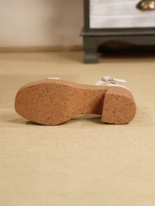 Primer plano de la suela marrón moteada y el tacón grueso de estas sandalias.