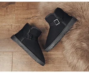 Classic black suede snow boots with metal buckle detail on warm faux fur background