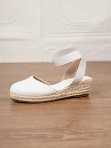 Perfil lateral de alpargatas de cuña de lona blanca con detalle de paja trenzada