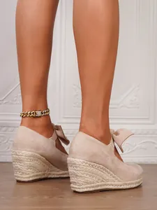 Primer plano de alpargatas de cuña cerradas en ante beige con suela de yute de moda