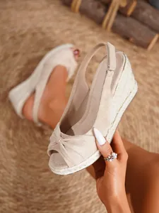 Vista detallada de sandalias de cuña en ante beige con nudo decorativo y suela cuerda