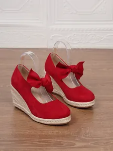 Detalle de sandalias rojas de cuña cerrada con lazo de ante y suela de cuerda