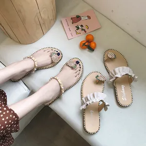 Macro detail of fashionable women's flat flip-flop sandals with pearl pineapple decor.