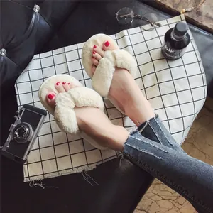 Nahaufnahme von gemütlichen beigen Plüsch-Flip-Flops getragen mit Jeans auf Karo