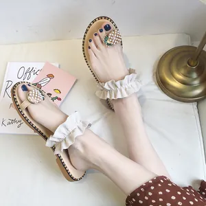 Elegant flat women's thong sandals featuring ruffle straps and pearl pineapple ornaments.