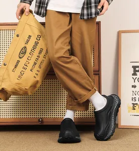 Man wearing black chunky fleece-lined clogs with thick soles in a cozy indoor setting