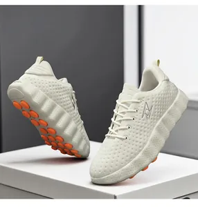 Detailed view of beige chunky sneakers featuring orange dotted non-slip soles and metal logo.
