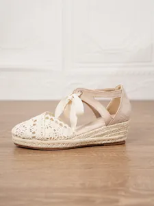 Vista lateral detallada de sandalias de cuña espadrilles con encaje beige y cinta