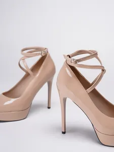 Primer plano de tacones de charol beige con plataforma y correas al tobillo