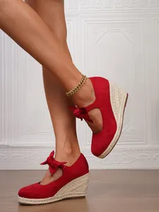 Elegante vista lateral de alpargatas de cuña en ante rojo con lazo y suela de esparto