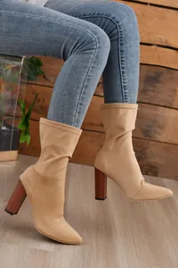 Nahaufnahme der eleganten beigen Stretch-Stiefel mit spitzer Kappe und klobigen Holzabsätzen