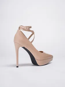 Vista lateral de zapatos de tacón de aguja en charol nude con plataforma y tira al tobillo