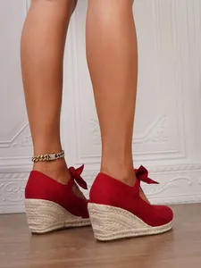 Primer plano de sandalias alpargatas con cuña de ante rojo con plataforma y lazo