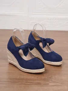 Vista lateral detallada de sandalias de cuña azules con plataforma de esparto y lazo
