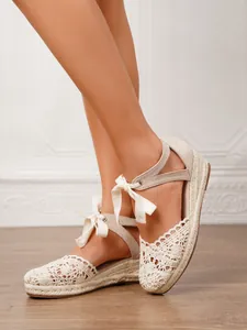 Detalle de elegantes sandalias de cuña de ganchillo con tiras al tobillo de lazo de cinta