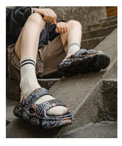 Close-up of men's graffiti print platform sandals on stone steps
