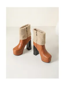 Detail view of brown faux leather ankle boots with platform heels and shearling trim