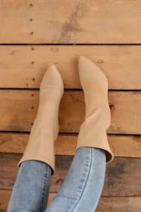 Detaillierte Ansicht beiger spitzer Stretch-Stiefel mit Blockabsatz auf Holzhintergrund