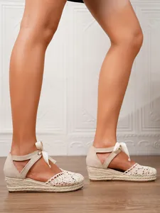 Alpargatas de cuña de encaje beige para mujer mostradas en los pies en un entorno real.