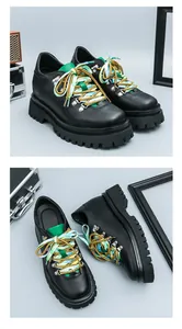 Vista dettagliata di scarpe nere con suola a carrarmato, lacci colorati e linguetta verde.