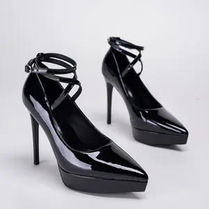 Elegantes tacones de charol negro con punta fina, plataforma y tiras cruzadas al tobillo.