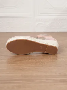 Primer plano de la suela de goma antideslizante de una sandalia de cuña tipo alpargata rosa