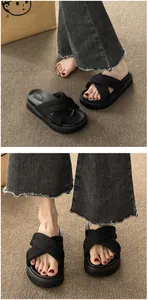 Close-up of women's black platform sandals with cross-over fabric straps on brown carpet