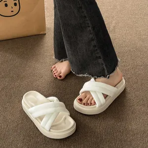 Detail showing white cross-strap platform slides on textured carpet background.