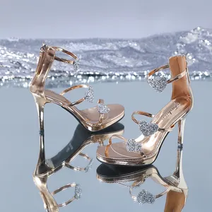 Detail view of gold metallic stiletto sandals with sparkly heart-shaped rhinestones.