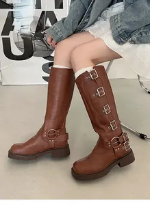 Detail of brown knee-high western boots featuring multiple metallic buckle straps.