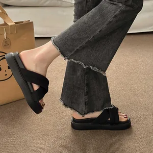 Close-up of women's black platform cross strap sandals with frayed denim jeans