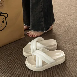 Close-up of cream-colored platform slippers featuring thick soles and ribbed criss-cross straps