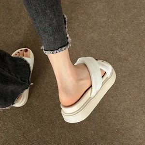 Detailed view of women's cream platform cross-strap sandals on a textured carpet background