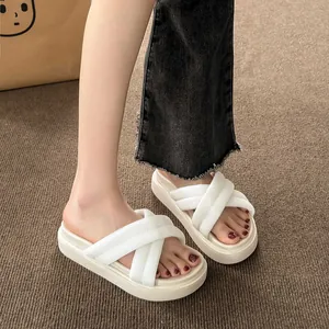Close-up of white cross-strap platform slippers worn on feet with a textured rug background