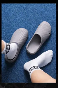 Top view of grey textured non-slip clogs worn with white socks on blue mat