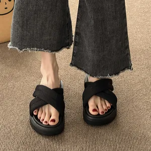 Close-up on-foot view of black platform sandals featuring criss-cross fabric straps