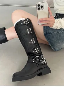 Detailed view of black knee-high boots with silver buckles on an Asian model