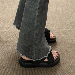 Detail view of black platform sandals with crossover straps and thick soles on feet